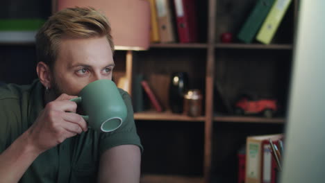 Handsome-man-drinking-coffee-and-looking-on-computer-screen