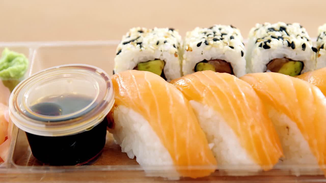rolos de sushi com salmão em recipiente de plástico