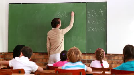 Pretty-teacher-teaching-math-to-her-class-and-smiling-at-camera