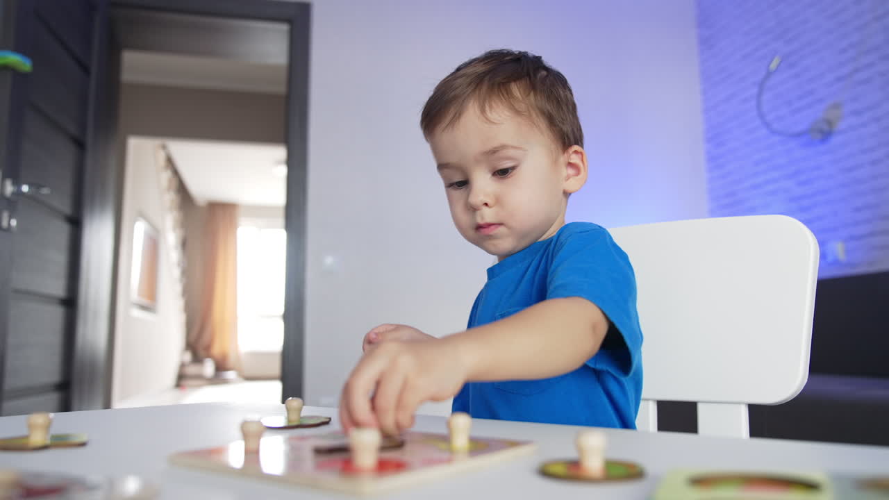 Sweet little kid playing at his desk at home. Lovely baby boy studying through the game. Low angle view.