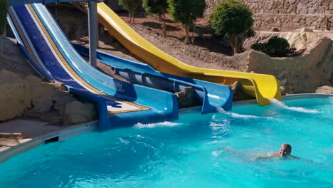niño en el tobogán acuático en el parque acuático. vacaciones de verano.