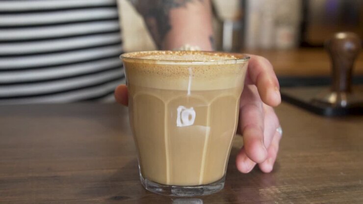 Barista serve un bicchiere di latte macchiato appena preparato sul bancone
