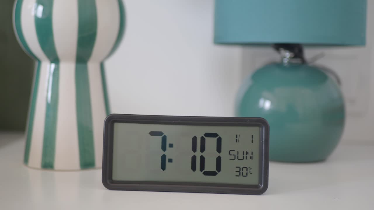 reloj despertador digital que muestra las 7:10 de la mañana en una mesa blanca