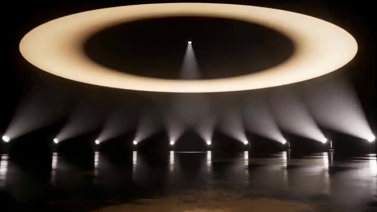 Ring lyser op og driver centralt downlight, skinnende scenegulv reflekterer varme stråler i dis