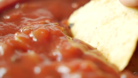 dipping tortilla chips in salsa