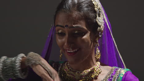 Close-Up-Of-Female-Kathak-Dancer-Performing-Dance-Wearing-Traditional-Indian-Dress-Seated-On-Floor-In-Spotlight-1