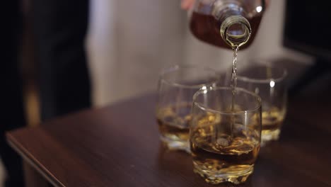 a man pouring whiskey into glasses