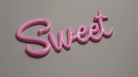 pink icing elegantly shaping the word sweet against a soft gray background, delivering a visually enticing and sugary message perfect for dessert lovers and celebrations