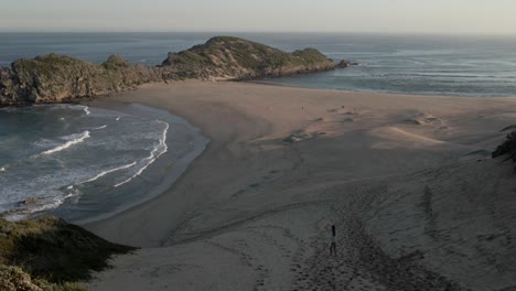 south africa young woman runs down a large sandy hill towards a beautiful beach peninsula