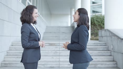 side view of two confident business colleagues in suits standing outside and talking