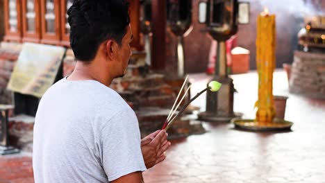 man holding incense sticks in prayer