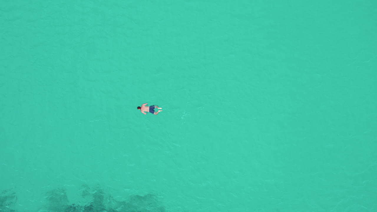 Aerial View Of AMan Swimming in the Calm Ocean near Playa del Trench, Mallorca, Spain