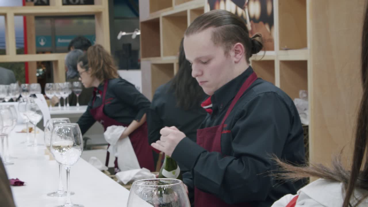 Wine tasting, busy counter, employees pouring for crowd at FITUR tourism conference, Madrid