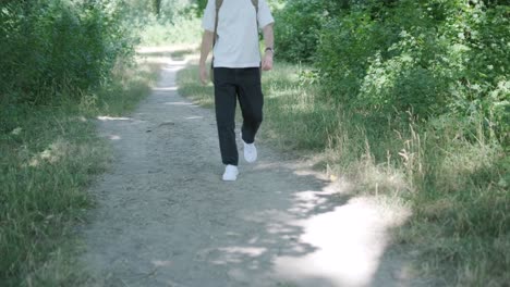 young man walking with guitar on street near forest