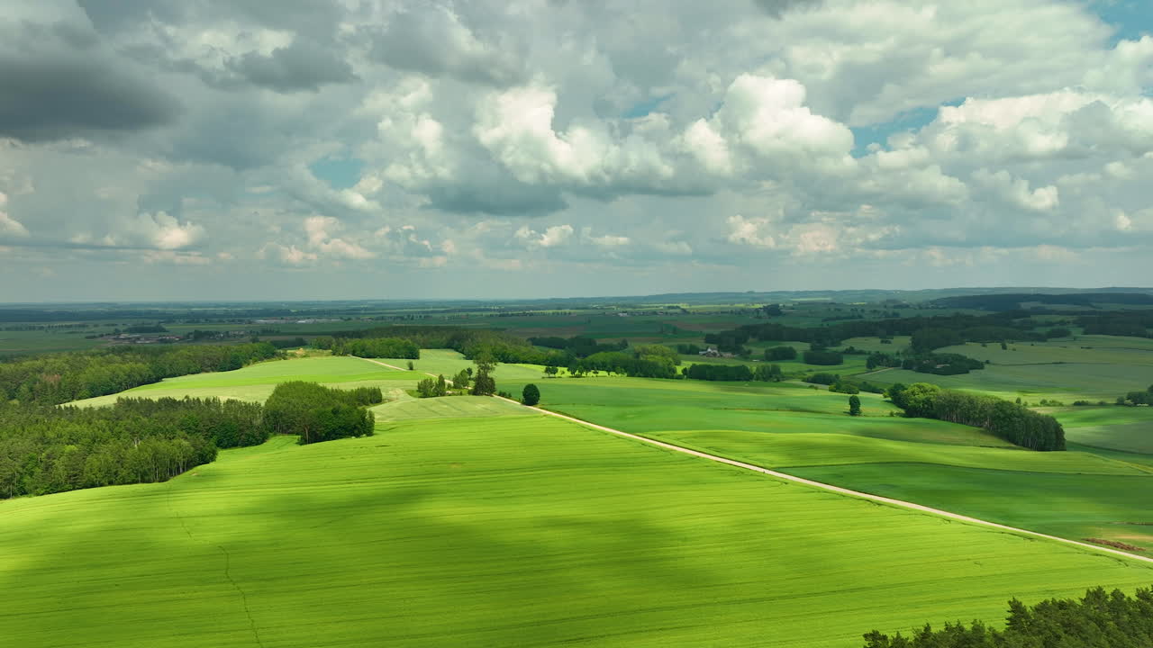 Aerial footage a wide expanse of lush green fields under a partly cloudy sky, emphasizing the beauty of rural landscapes and natural environments