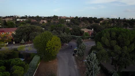 Drone-Rastreando-A-Un-Automovilista-Haciendo-Un-Círculo-De-Tráfico-En-Una-Lujosa-Urbanización-Residencial