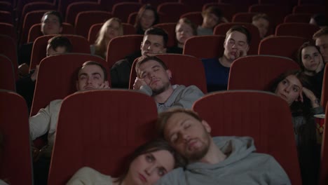 bored audience watching film in cinema. spectators fall asleep from boring film