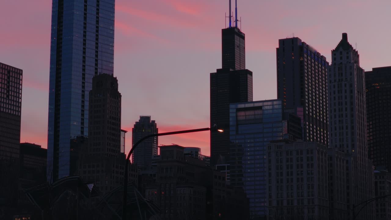 Al caer el crepúsculo, los rascacielos de Chicago se alzan imponentes contra un vibrante cielo rosa y morado. Ideal para proyectos de temática urbana o fondos de paisajes urbanos.