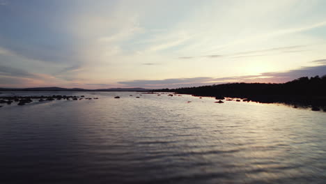 Beautiful-aerial-flying-over-stoney-shore-and-water-of-irish-lough-corrib-with-many-small-island-silhouettes-in-the-water