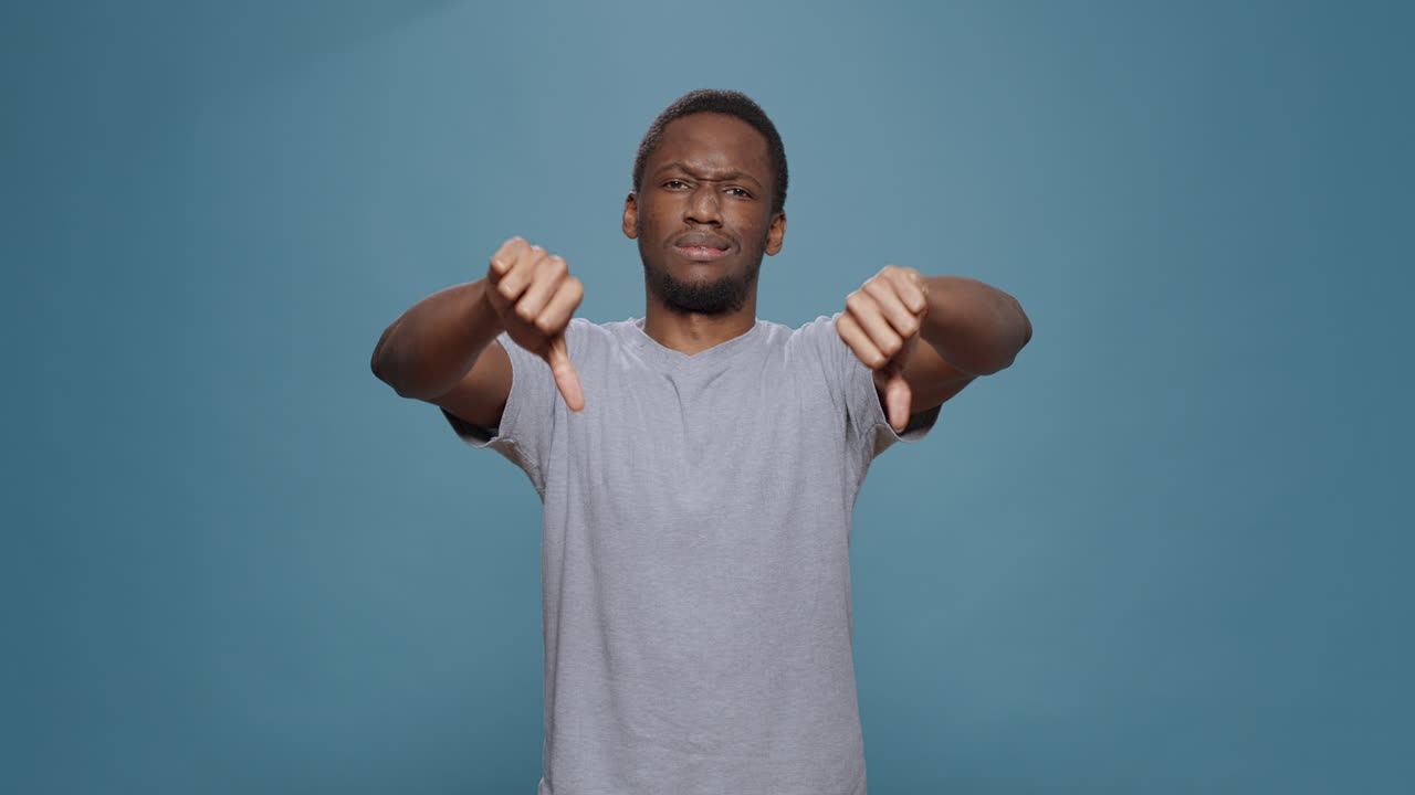 Disappointed person showing thumbs down symbol in studio