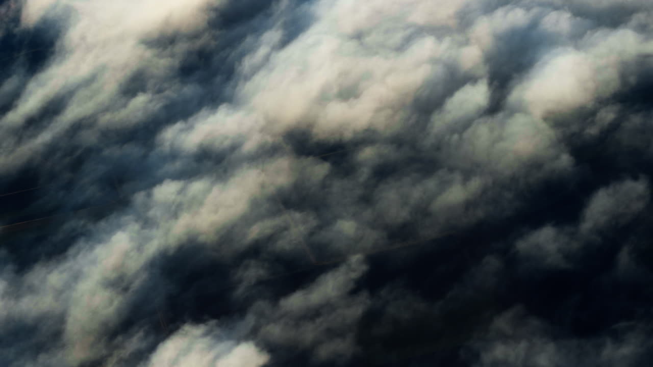 Aerial view of dense dramatic clouds seen from airplane above Europe. Abstract cloudscape with deep shadows and sunlight creating textured sky background