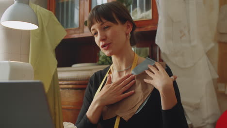 woman discussing fabric on online video call in dressmaking studio