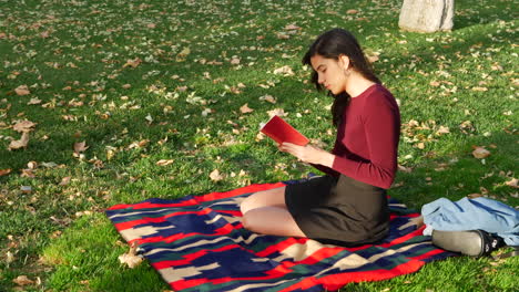 A-young-woman-school-girl-reading-a-book-on-a-campus-lawn-or-outdoor-park-SLOW-MOTION