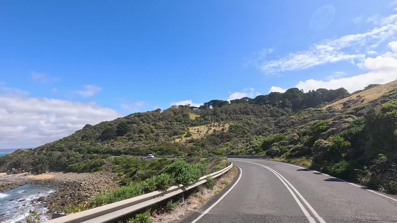 A 14-second video capturing a drive along the picturesque Great Ocean Road, showcasing coastal views and lush greenery under clear skies