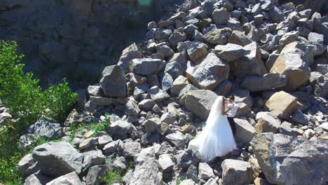bride and groom hugging. aerial shot of a wedding couple staying over stones landscape