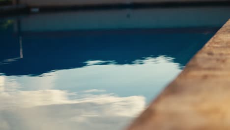 Primer-Plano-Del-Agua-De-La-Piscina-Ondeando-Y-Ondeando-Con-El-Reflejo-De-Un-Cielo-Azul-En-El-Agua.