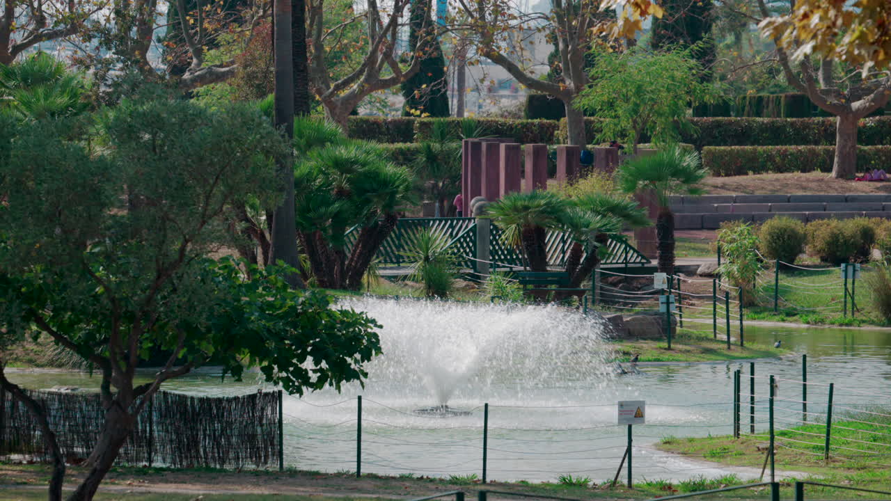 A water fountain surrounded by palm trees and greenery in a park in Cannes, France