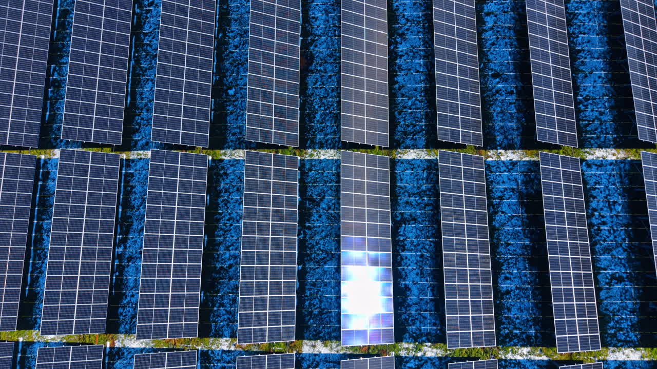 Vista dall'alto di una griglia di pannelli fotovoltaici con bagliore solare. Vista aerea simmetrica dall'alto di celle solari, caratterizzata da un brillante riflesso della luce solare.
