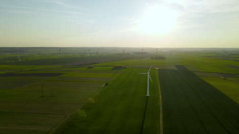 Parque-Eólico-Sobre-Campos-Verdes-Al-Atardecer-Visto-Desde-Un-Punto-Alto,-Vista-Aérea-De-Turbinas-Eólicas-Girando-Lentamente-Bajo-El-Viento-En-Puck,-Pomorskie,-Polonia,-Drone-Aéreo