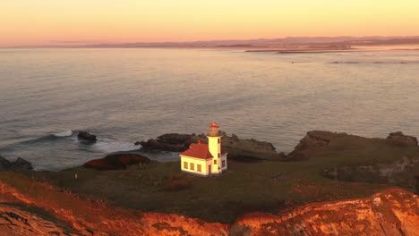 cape arago lighthouse illuminated by setting sun, oregon coast 4k drone