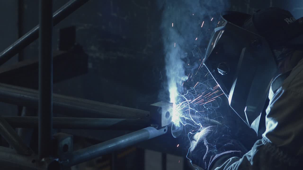 Welder working on a pipe structure, using MIG welding procedure.
