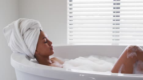 african american woman relaxing in the bath tub in the bathroom at home