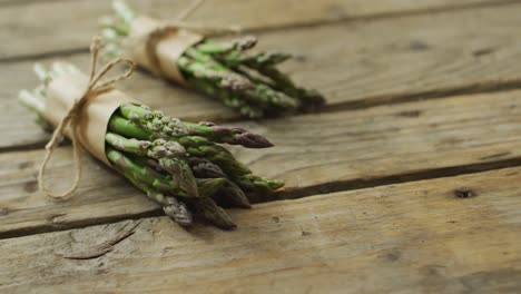 video of two fresh asparagus bundles with copy space on wooden background