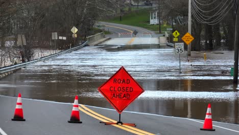 road closed ahead sign with flooded bridge after heavy rainfall in usa