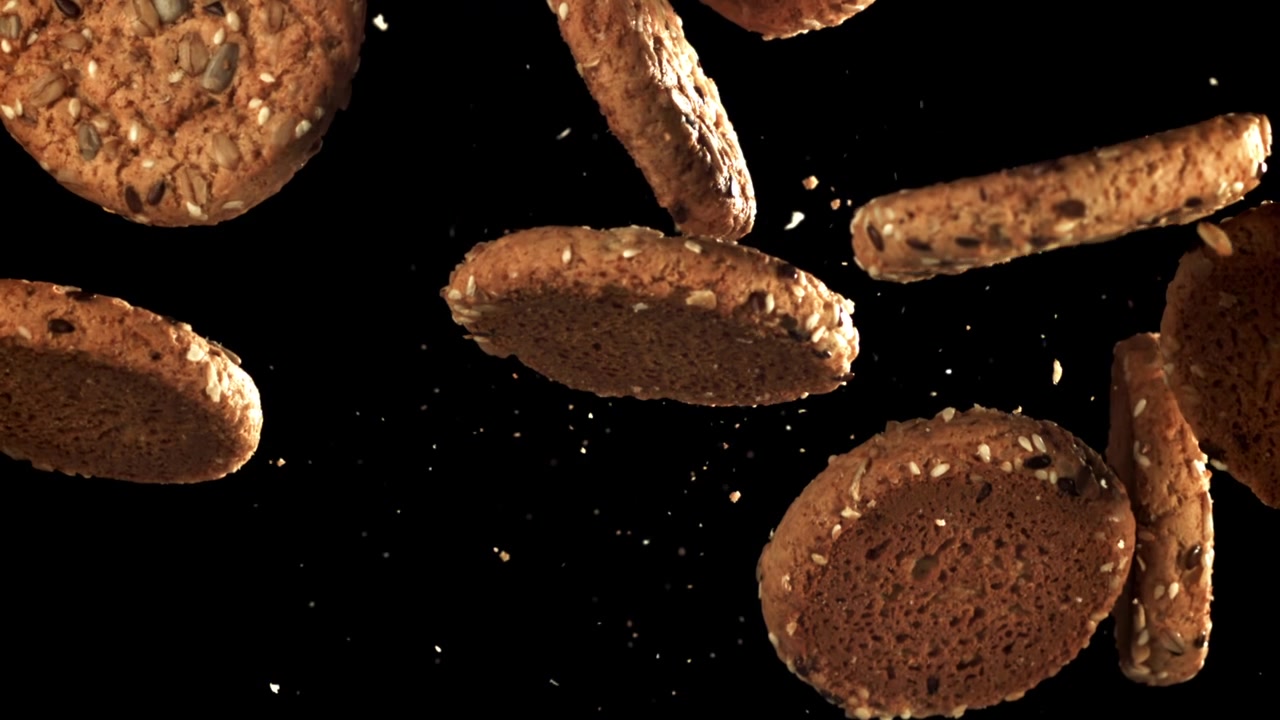 Seeded Oatmeal Cookies Falling in Slow Motion on Black Background