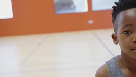 in school gym, boy standing and smiling, enjoying physical education class