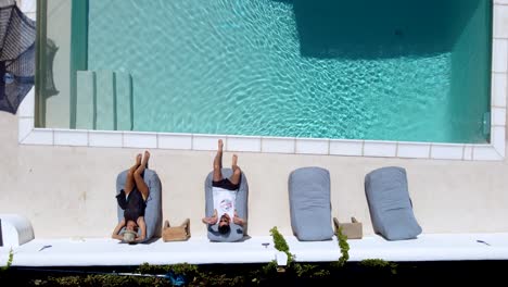 aerial top view over a couple seated and relaxing on hotel pool terrace, paros