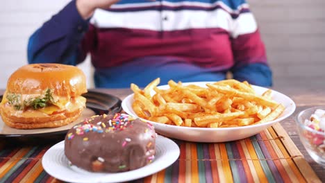 una comida no saludable con hamburguesas, papas fritas, rosquillas y palomitas de maíz