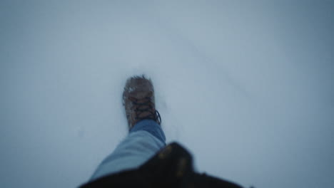 Top-down-view-of-male-legs-in-winter-sport-shoes-walking-on-fresh-snow