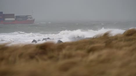 stormy weather at sea with container ship and coastal dunes