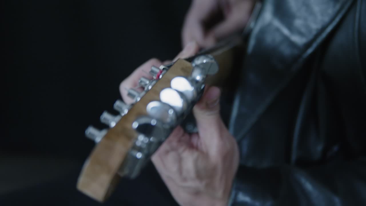 Electric guitar detail: Pull focus from headstock to body as man plays