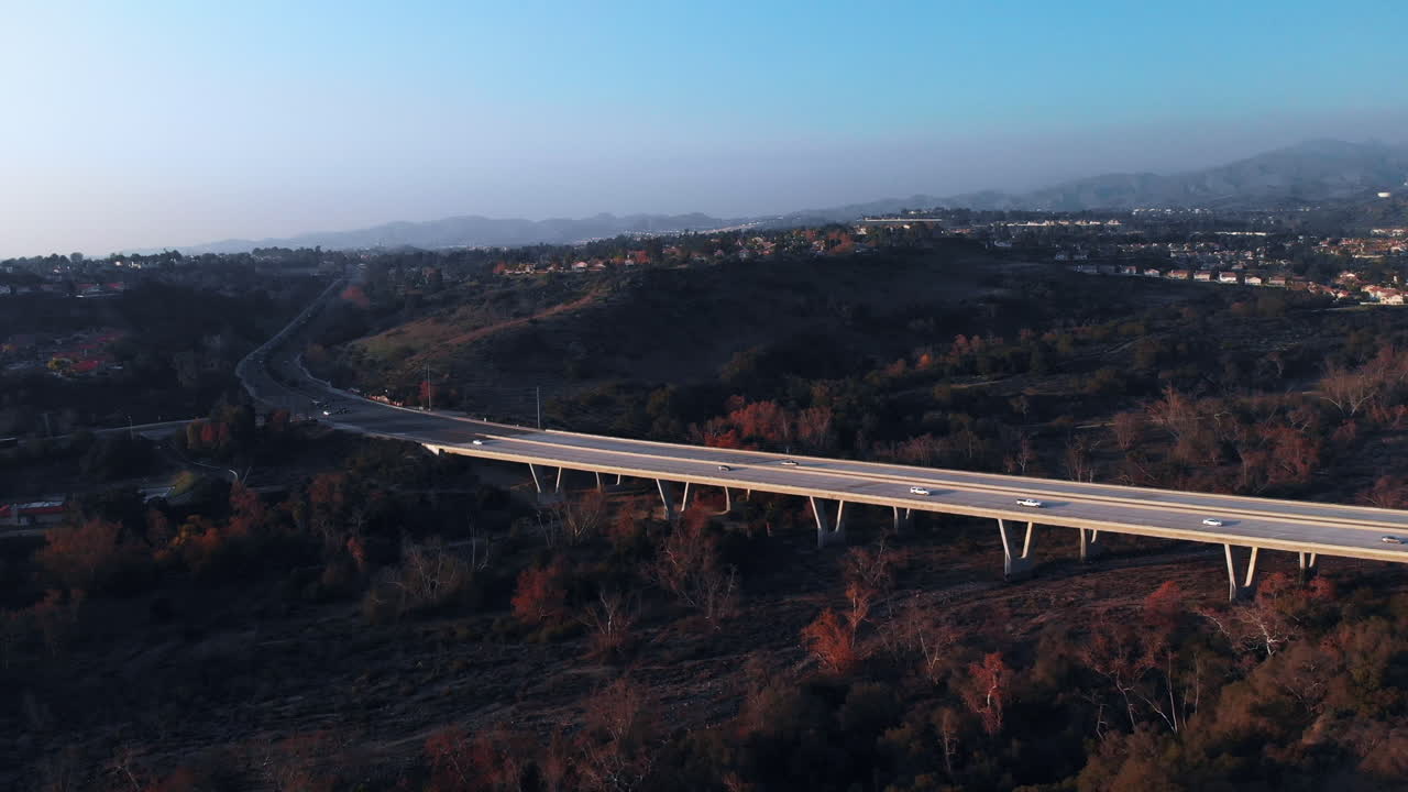 교외 도시에서 일몰에 다리로 뒤로 비행하는 공중 샷