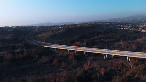 aerial shot flying backwards by a bridge at sunset in a suburban city