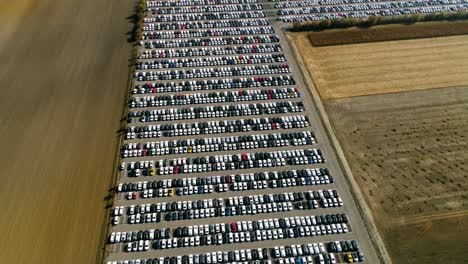 aerial footage of finished cars ready to be shipped on huge distribution center