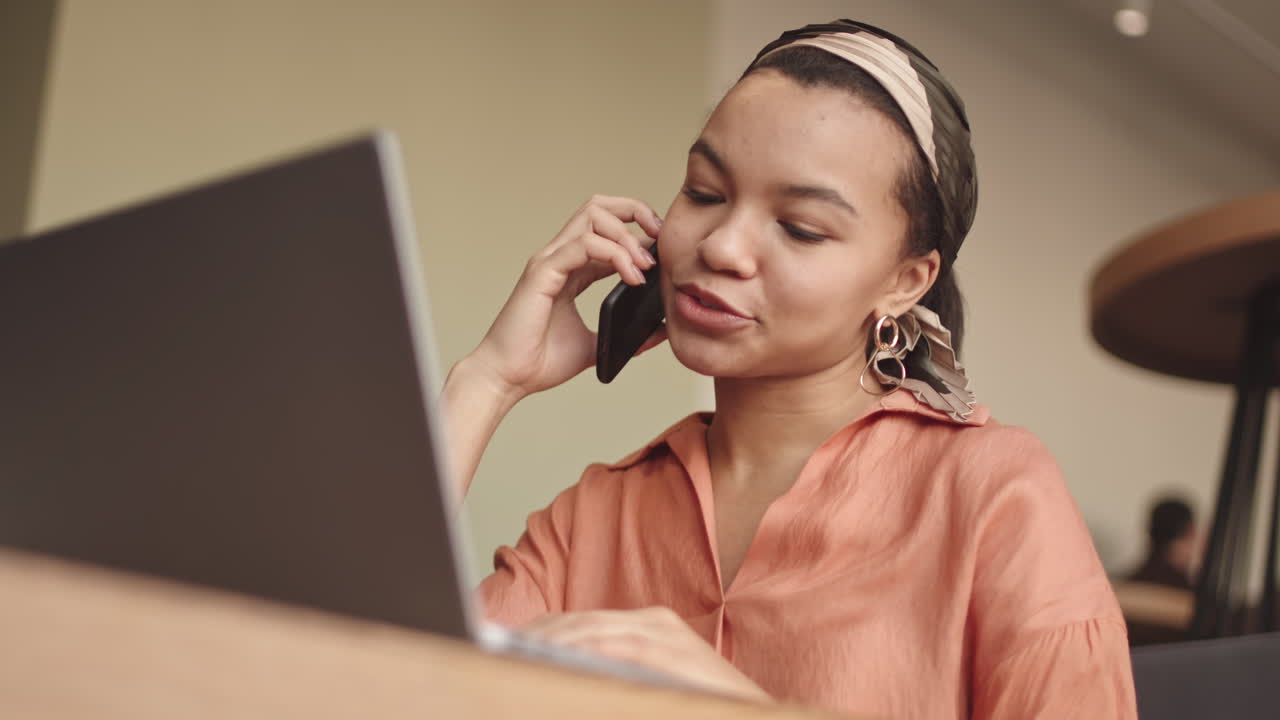 Female Freelancer Talking on Mobile Phone in Cafe