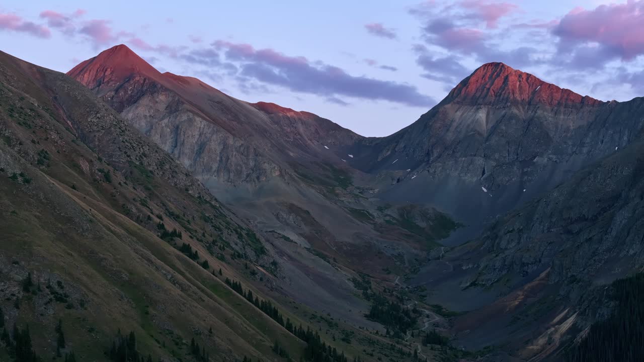 Drone melintasi puncak-puncak Alpen yang curam dengan cahaya terakhir matahari terbenam di American Basin, Trans America Trail, Colorado, USA